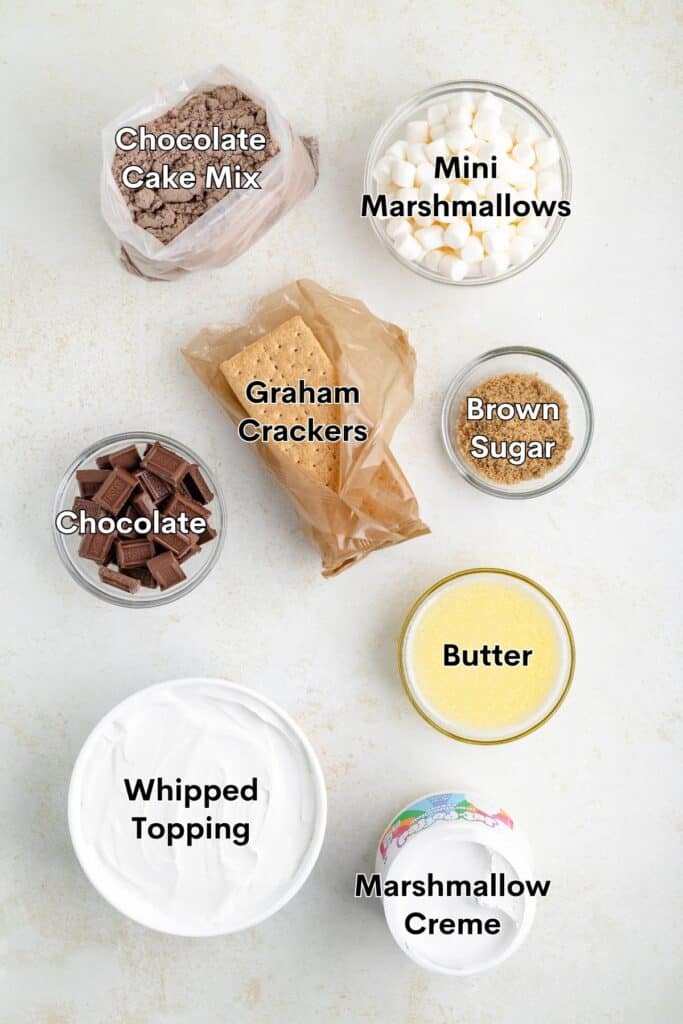 Top-down view of labeled dessert ingredients: cake mix, marshmallows, graham crackers, chocolate, brown sugar, butter.