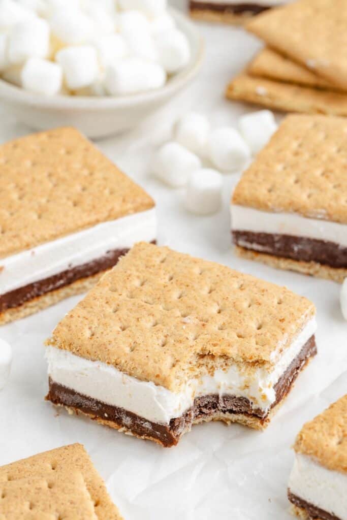 Close-up of smores bars, center bar with a bite taken out, mini marshmallows scattered behind.