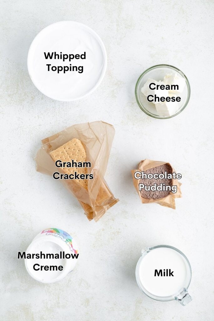 Six labeled ingredients on a light background: whipped topping, cream cheese, graham crackers, pudding, marshmallow creme, and milk.