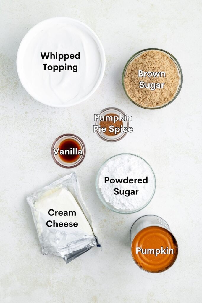 Bowls of dessert ingredients, including whipped topping and spices, arranged on a white surface.