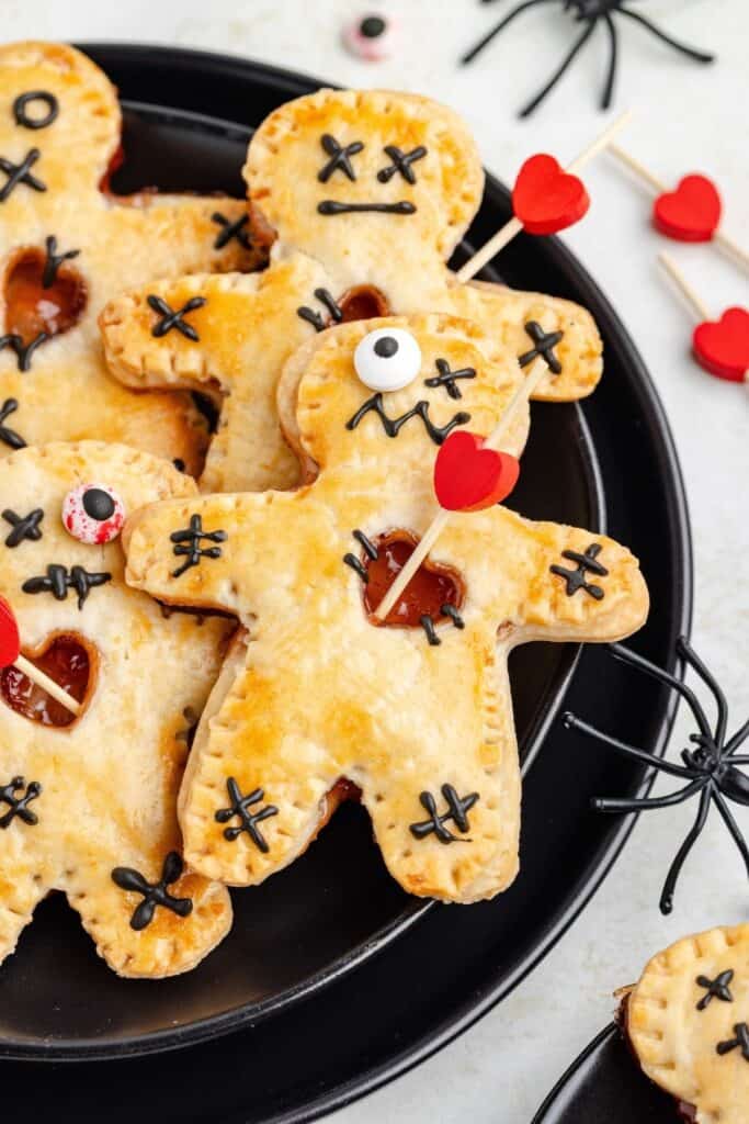 Gingerbread-shaped hand pies decorated as voodoo dolls with candy eyes, heart toothpicks, and toy spiders.