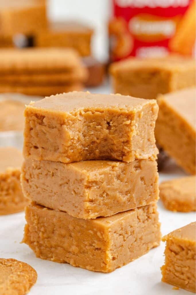 Three square Biscoff fudge pieces stacked, with a bite taken out of the top one.