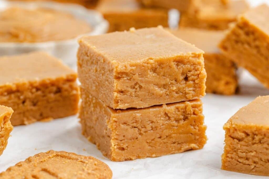 Two-ingredient Biscoff fudge surrounded by additional fudge pieces and a cookie.