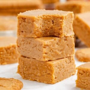 A stack of three square Biscoff fudge pieces with a bite taken out of the top.