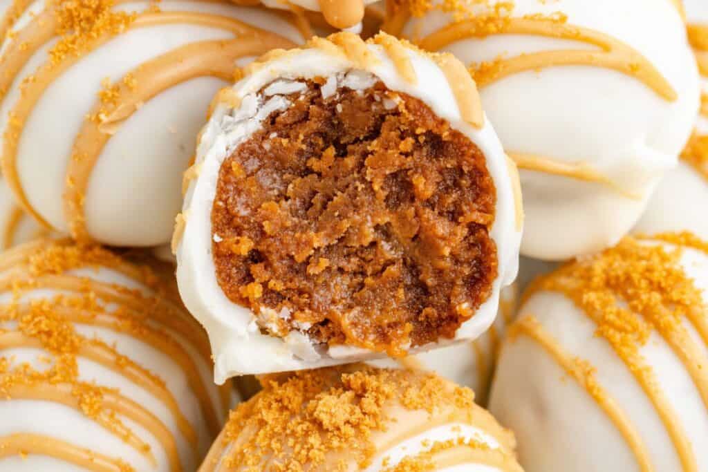 Biscoff truffles with cookie butter drizzle and crumbs, one halved to show the interior.