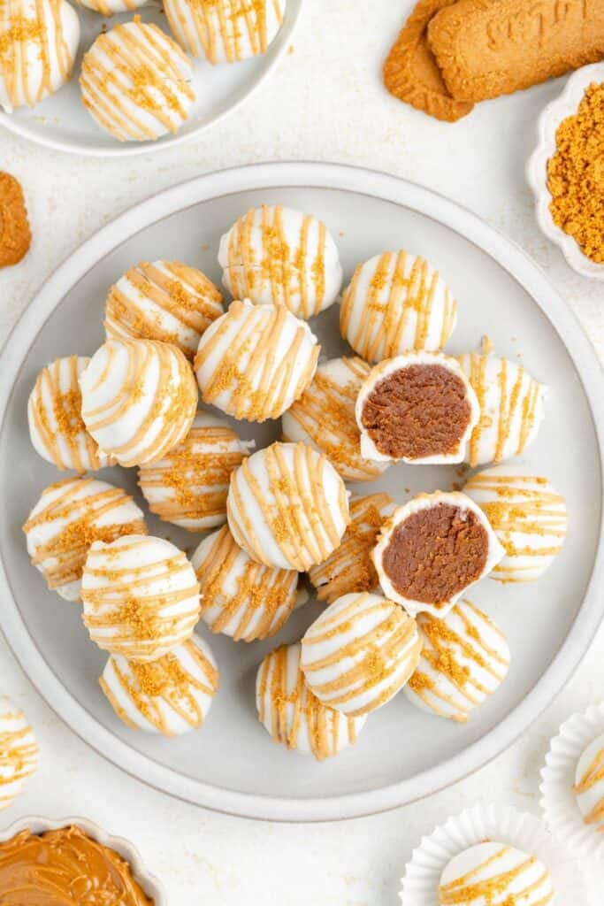 Biscoff no-bake truffles drizzled with cookie butter and topped with cookie crumbs on a plate.