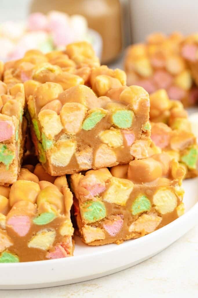 A stack of square-cut marshmallow peanut butter bars on a white plate.