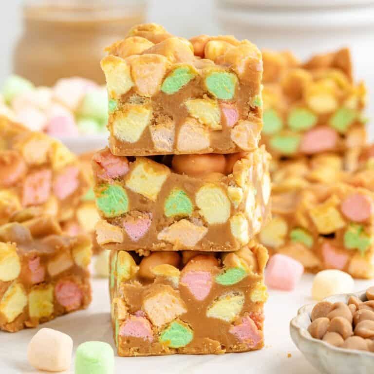 A stack of three square peanut butter marshmallow bars with colorful mini marshmallows.