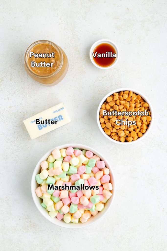 Ingredients for a recipe: peanut butter, vanilla extract, butter, butterscotch chips, and colorful mini marshmallows.